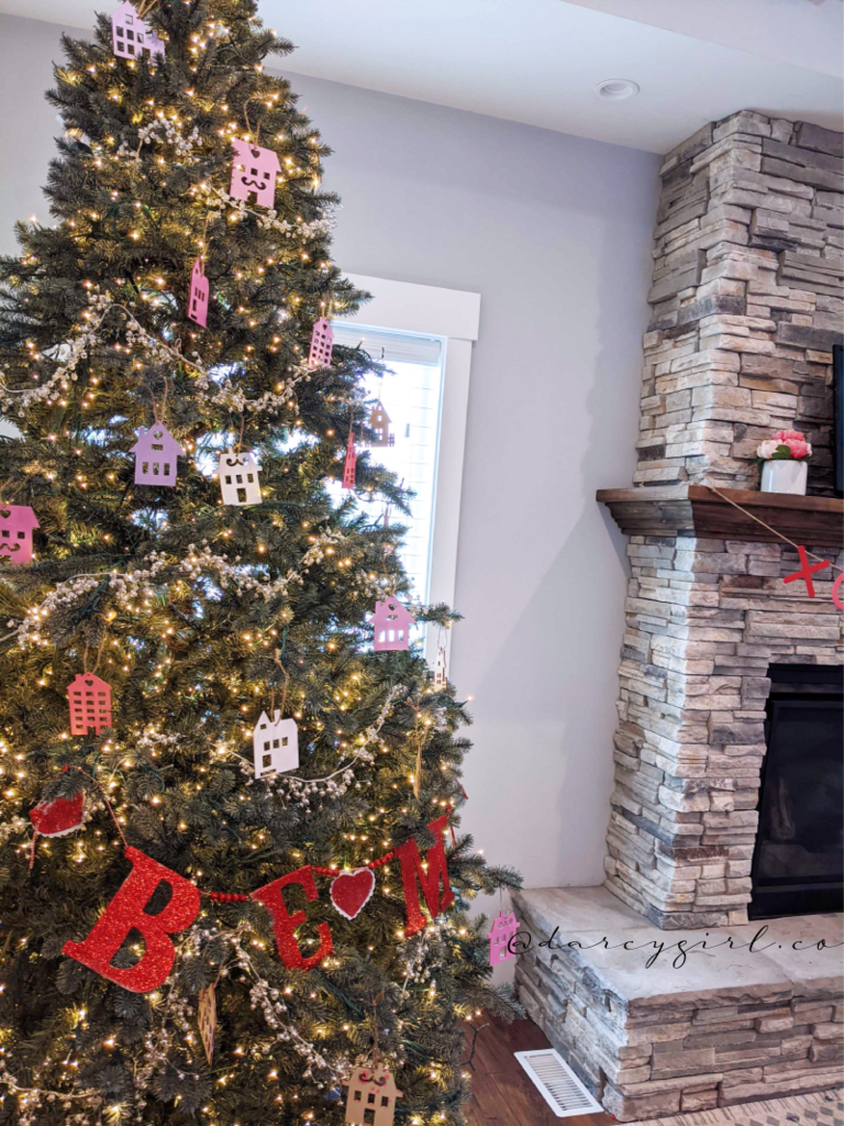 Christmas tree with pink and purple painted house ornaments and a garland that says, Be Mine.  