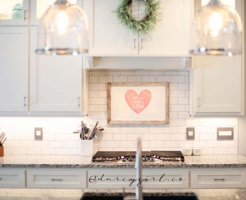 Kitchen with Valentine's Day sign, and a wreath above a stove. 